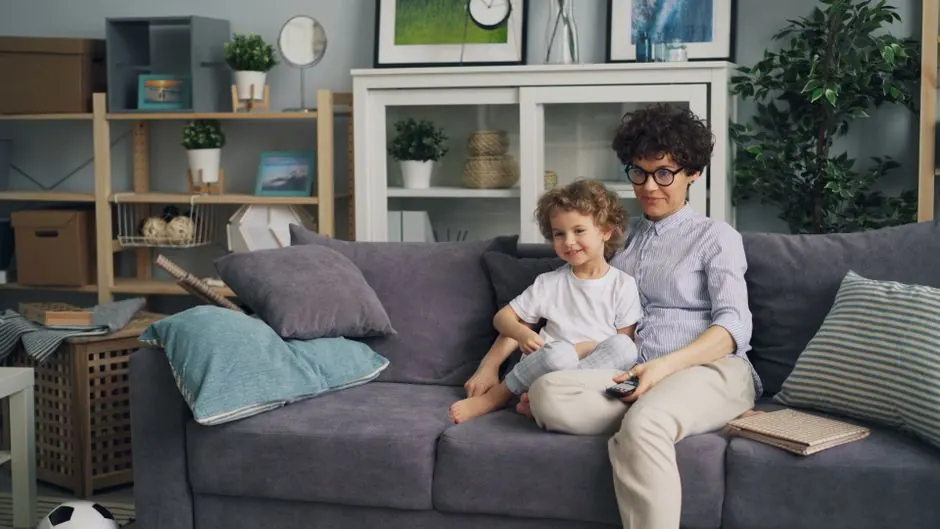 Mother and son sitting on a couch in a cozy living room, enjoying their time together.